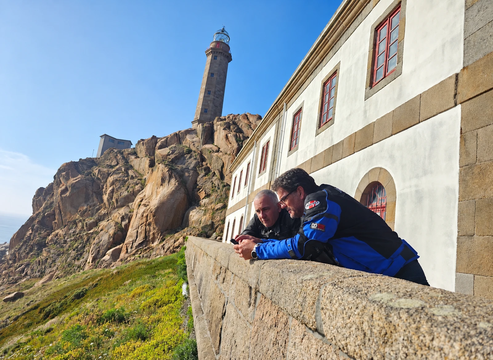 Two Changos leaning on a wall at a coastal viewpoint in Galicia, Spain
